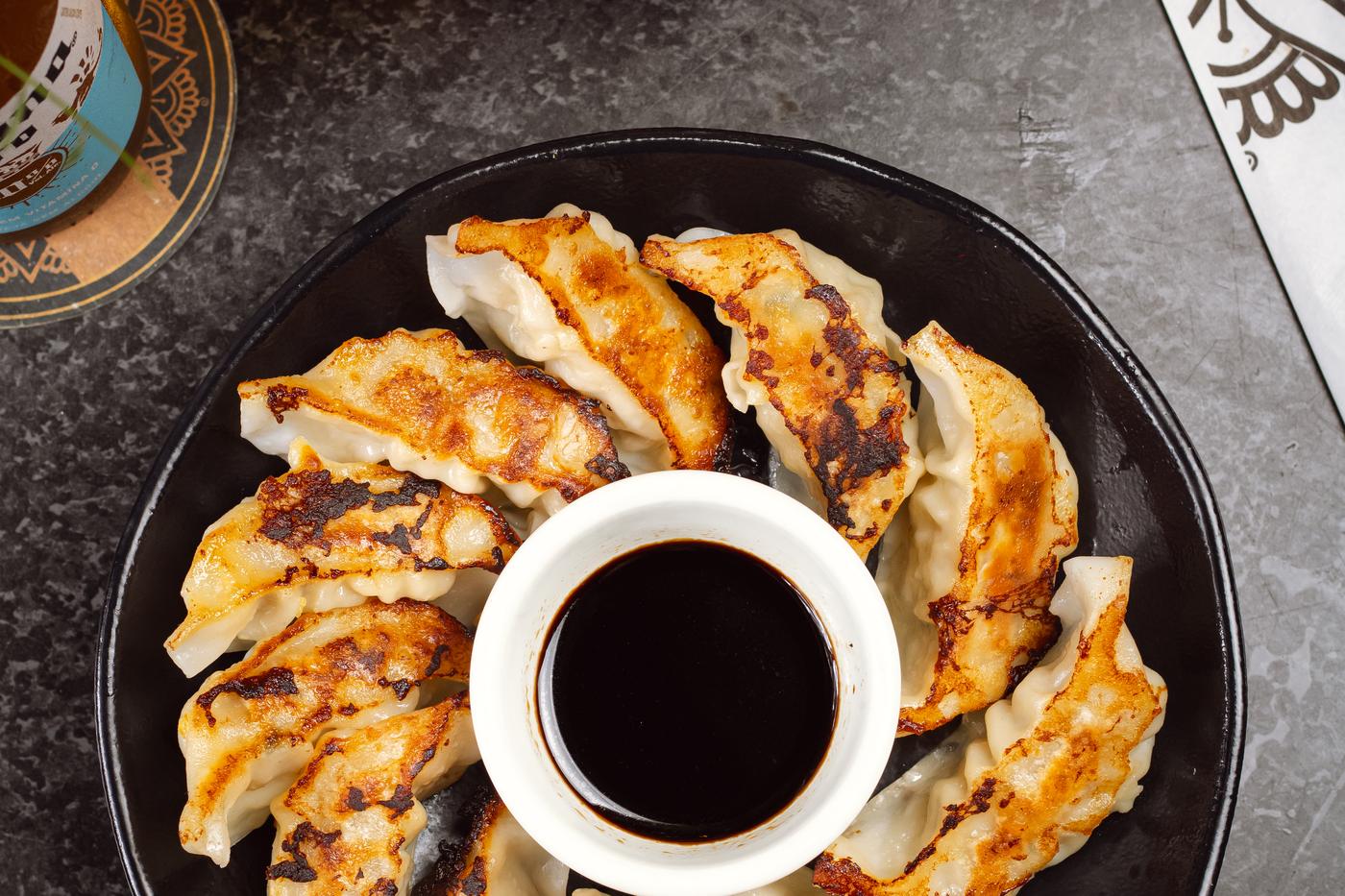 Porção de gyoza recheado com carne de porco, com molho no centro