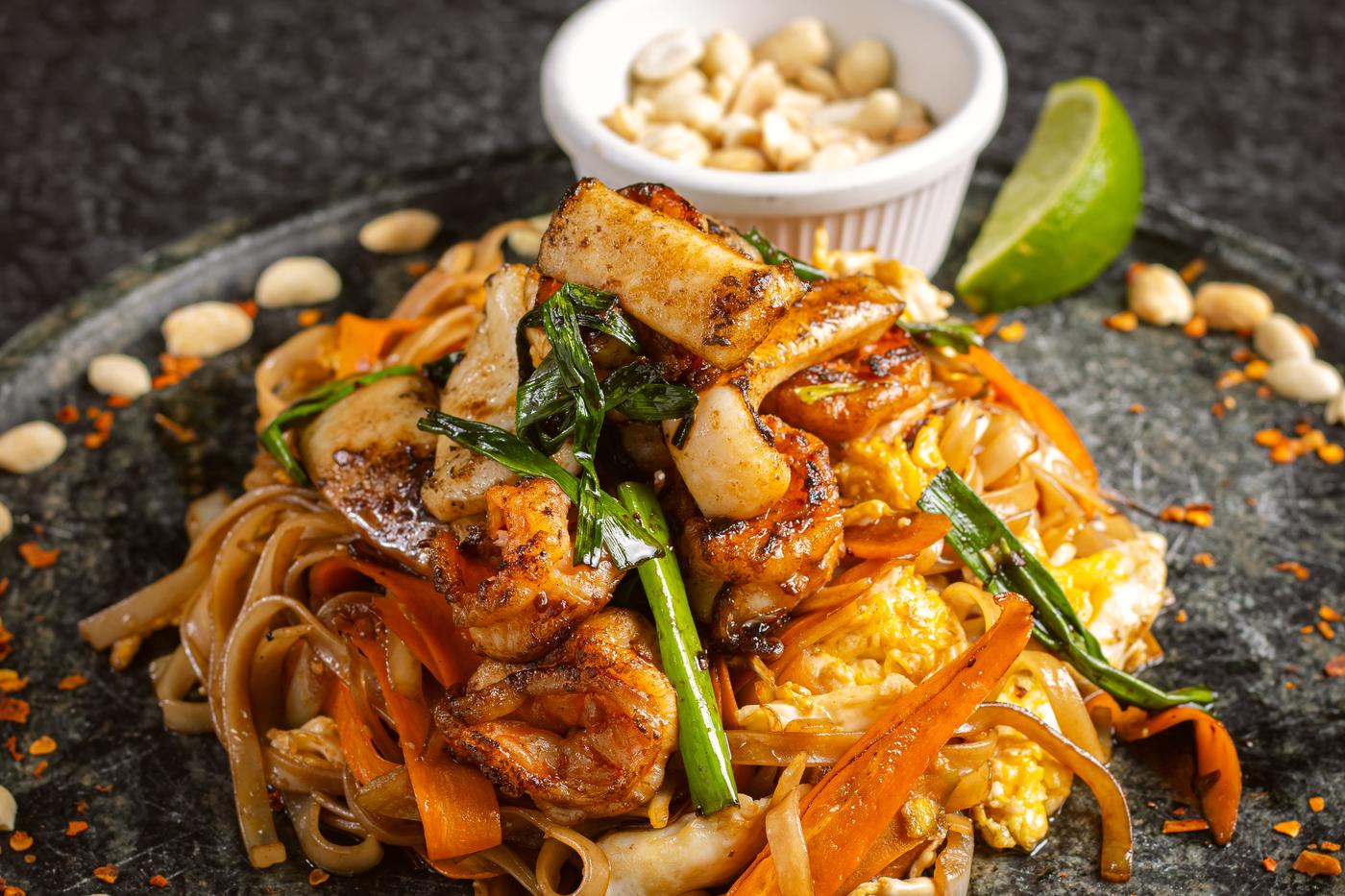Pad thai de camarão em prato de pedra, com amendoim e limão