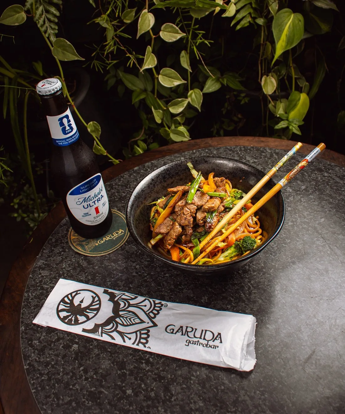 Yakisoba sendo salteado na chapa com fogo alto e vapor subindo